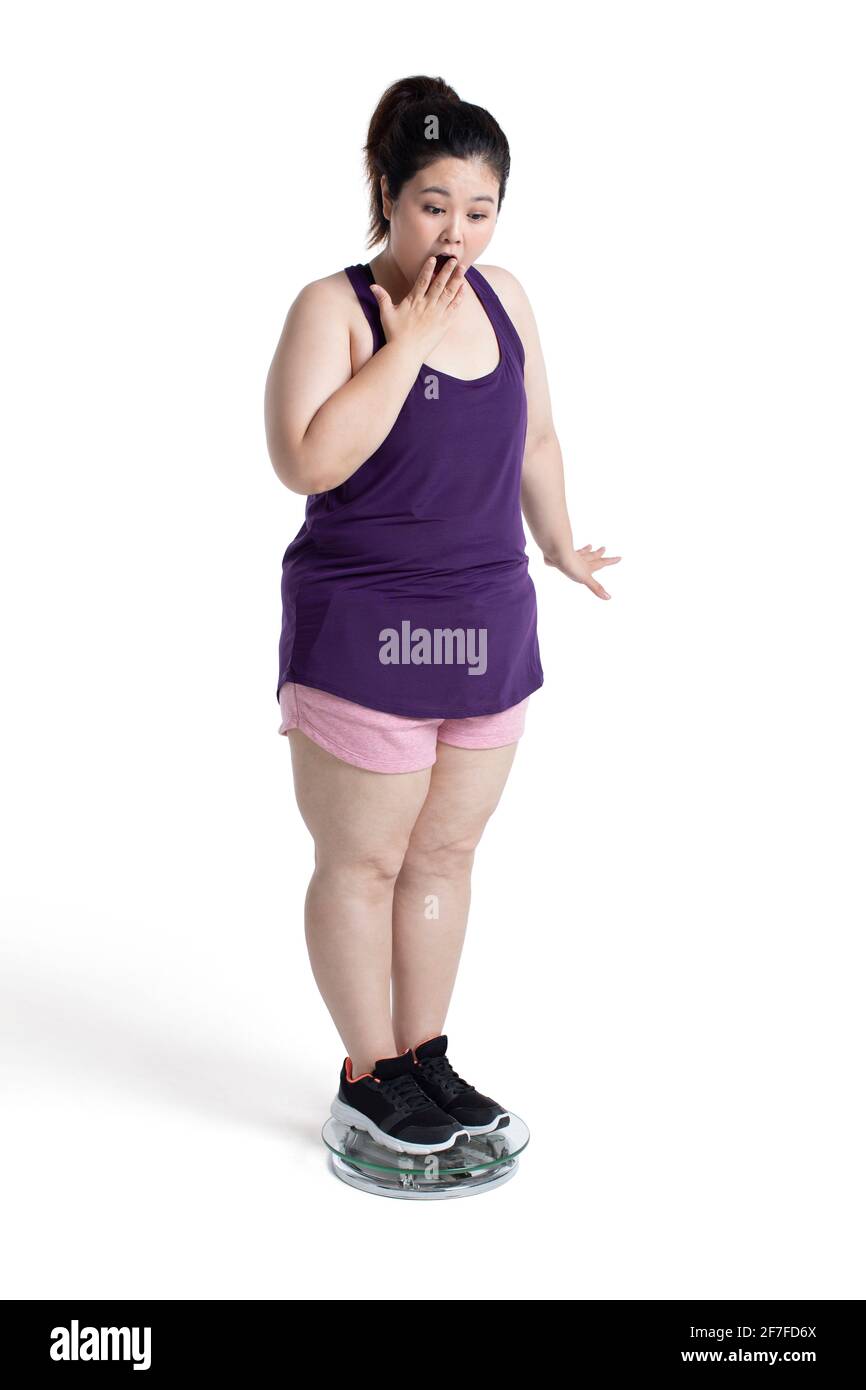Übergewichtige junge Frau, die sich auf einer Waage wiegt Stockfoto