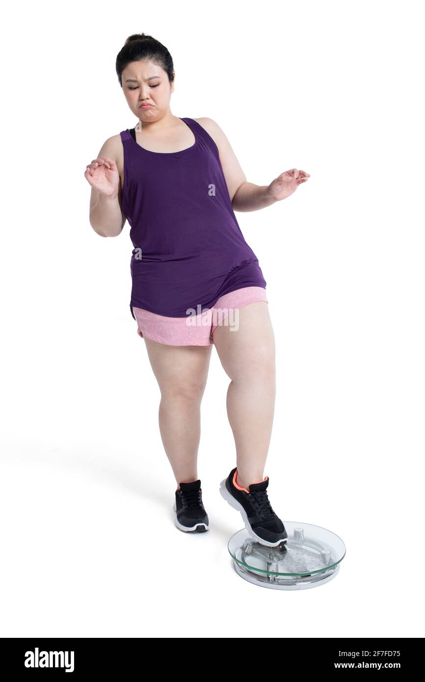 Übergewichtige junge Frau, die sich auf einer Waage wiegt Stockfoto