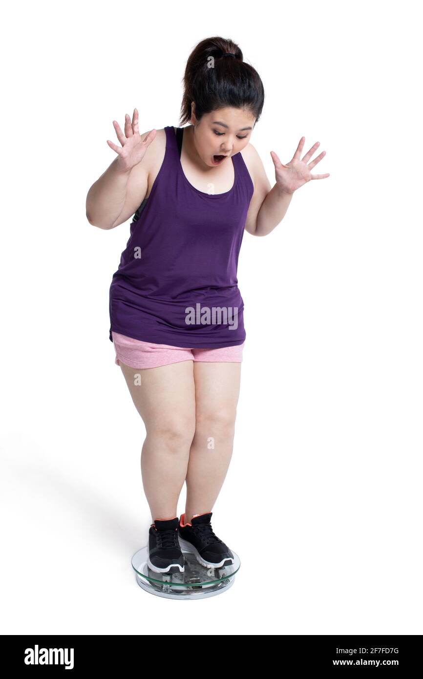 Übergewichtige junge Frau, die sich auf einer Waage wiegt Stockfoto