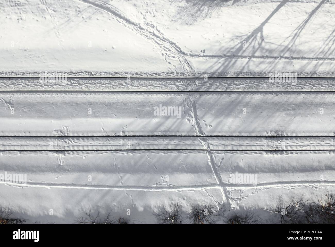 Luftaufnahme einer zweigleisigen Eisenbahn nach starkem Schneefall. Winterbahn mit weißem Schnee, Draufsicht. Verkehrsinfrastruktur, Bahnstrecke, verschneite l Stockfoto