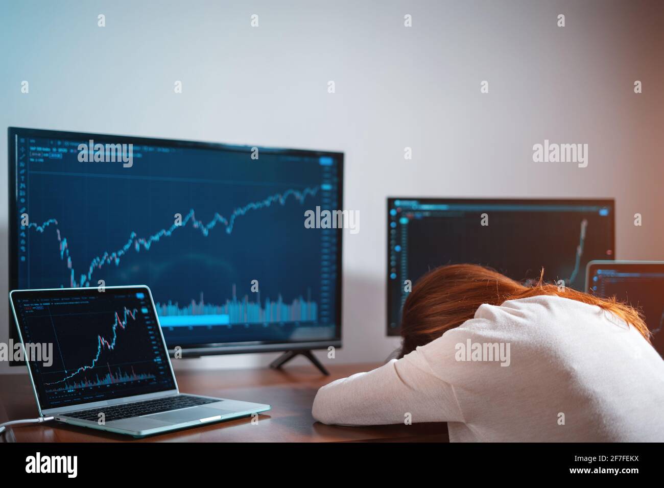 Müde weibliche Anfängertradlerin, die in der Nähe des Monitors mit Aktienchart schläft Am Arbeitsplatz Stockfoto