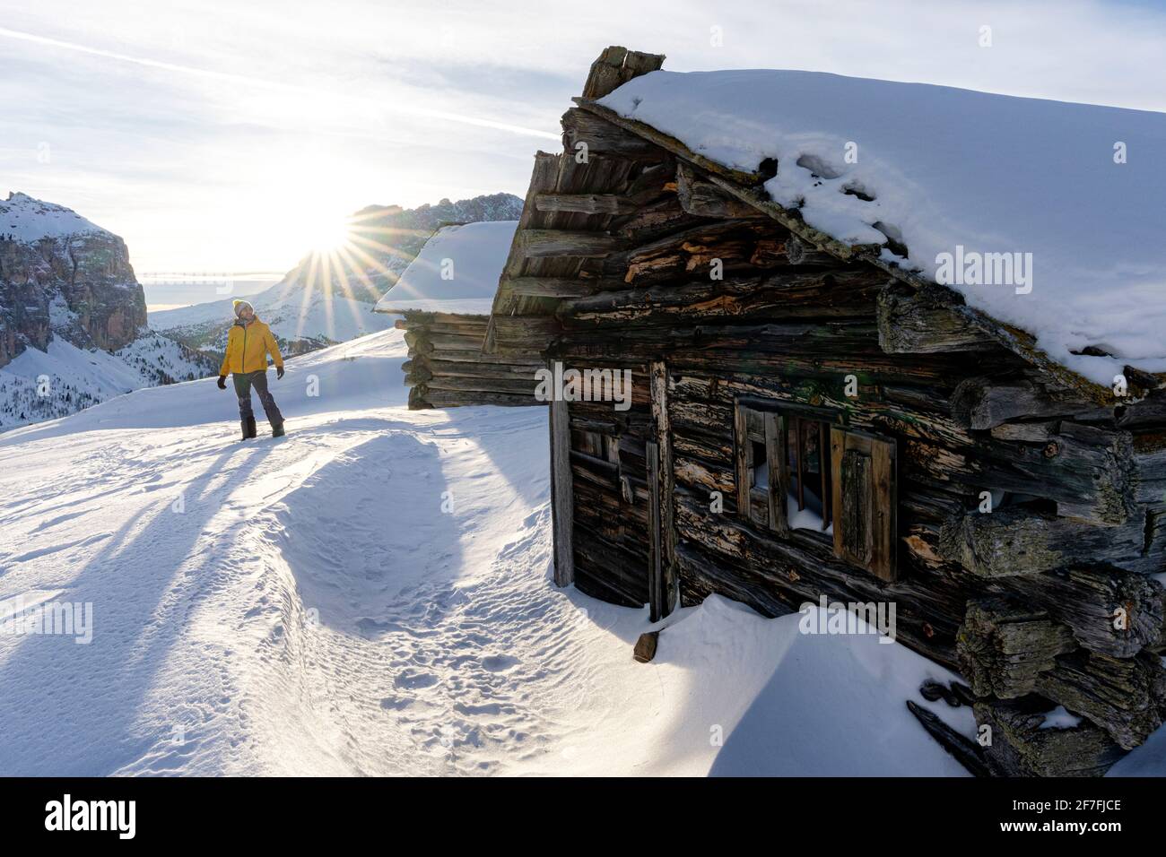 Wanderer in der verschneiten Landschaft, die im Winter vom hinterleuchteten Sonnenuntergang erhellt wird, Grödner Joch, Dolomiten, Südtirol, Italien, Europa Stockfoto