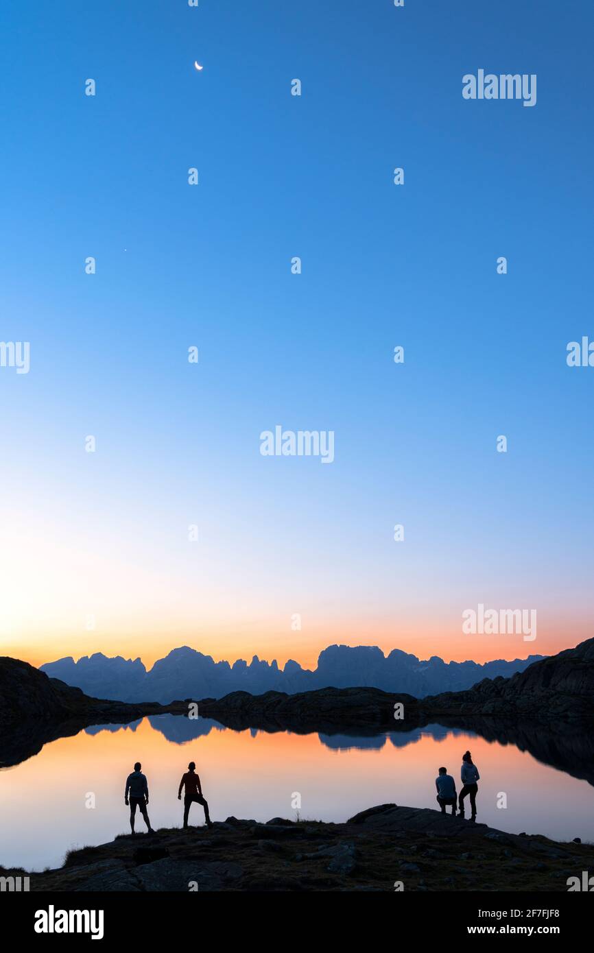 Wanderer, die die Brenta-Gruppe bewundern, spiegeln sich im Lago Nero di Cornisello in der Morgendämmerung, Trient, Trentino-Südtirol, Italien, Europa Stockfoto