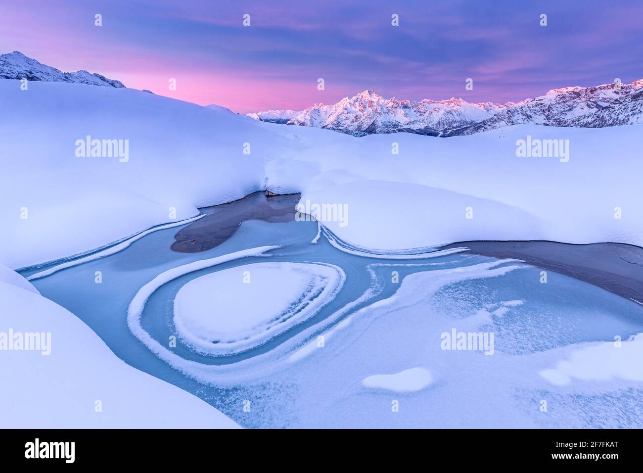Verrückte Form in einem gefrorenen alpinen See bei Sonnenaufgang mit Blick auf den Mount Disgrazia, Valmalenco, Valtellina, Lombardei, Italien, Europa Stockfoto