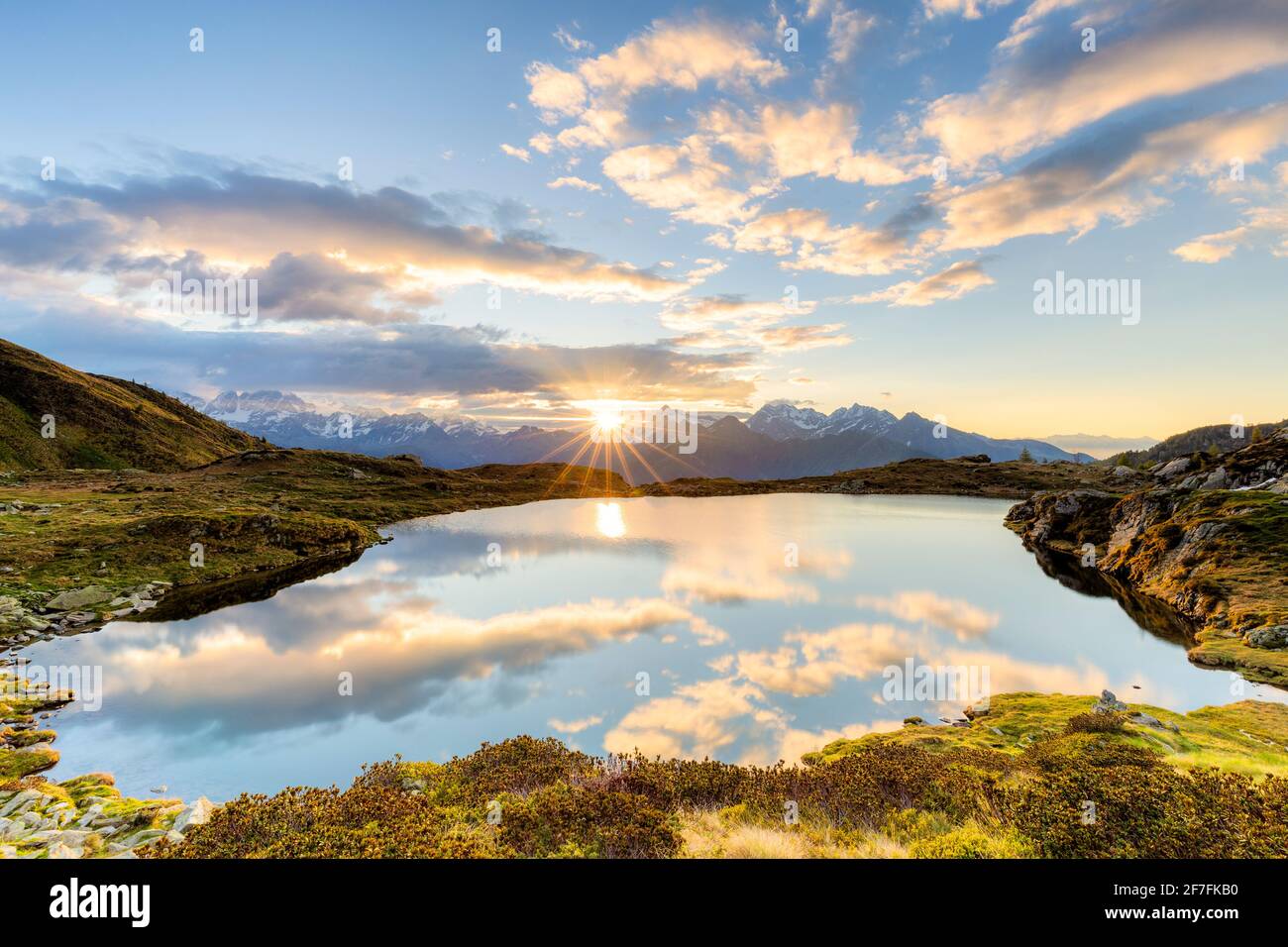 Die Sonne und die Wolken, die sich im Arcoglio-See bei Sonnenaufgang, Valmalenco, Valtellina, Lombardei, Italien, Europa Stockfoto