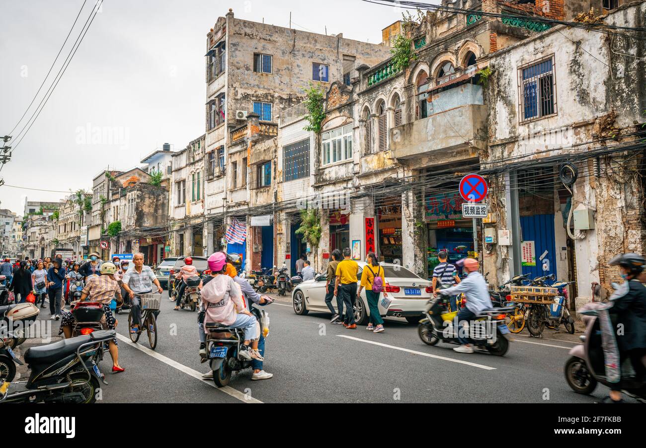Haikou China , 21 March 2021 : Straßenansicht der Haikou Altstadt mit alten heruntergefahrenen Gebäuden und überfüllten Boai Nordstraße mit Menschen und Motorroller in Stockfoto