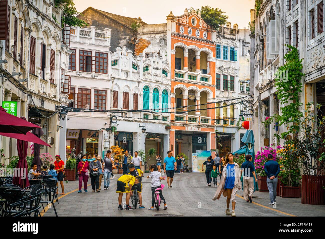 Haikou China , 21 March 2021 : Qilou alte Straße Blick auf eine Fußgängerzone mit bunten Arcade-Gebäude mit Menschen und dramatischen Sonnenuntergang Licht in Haikou Stockfoto