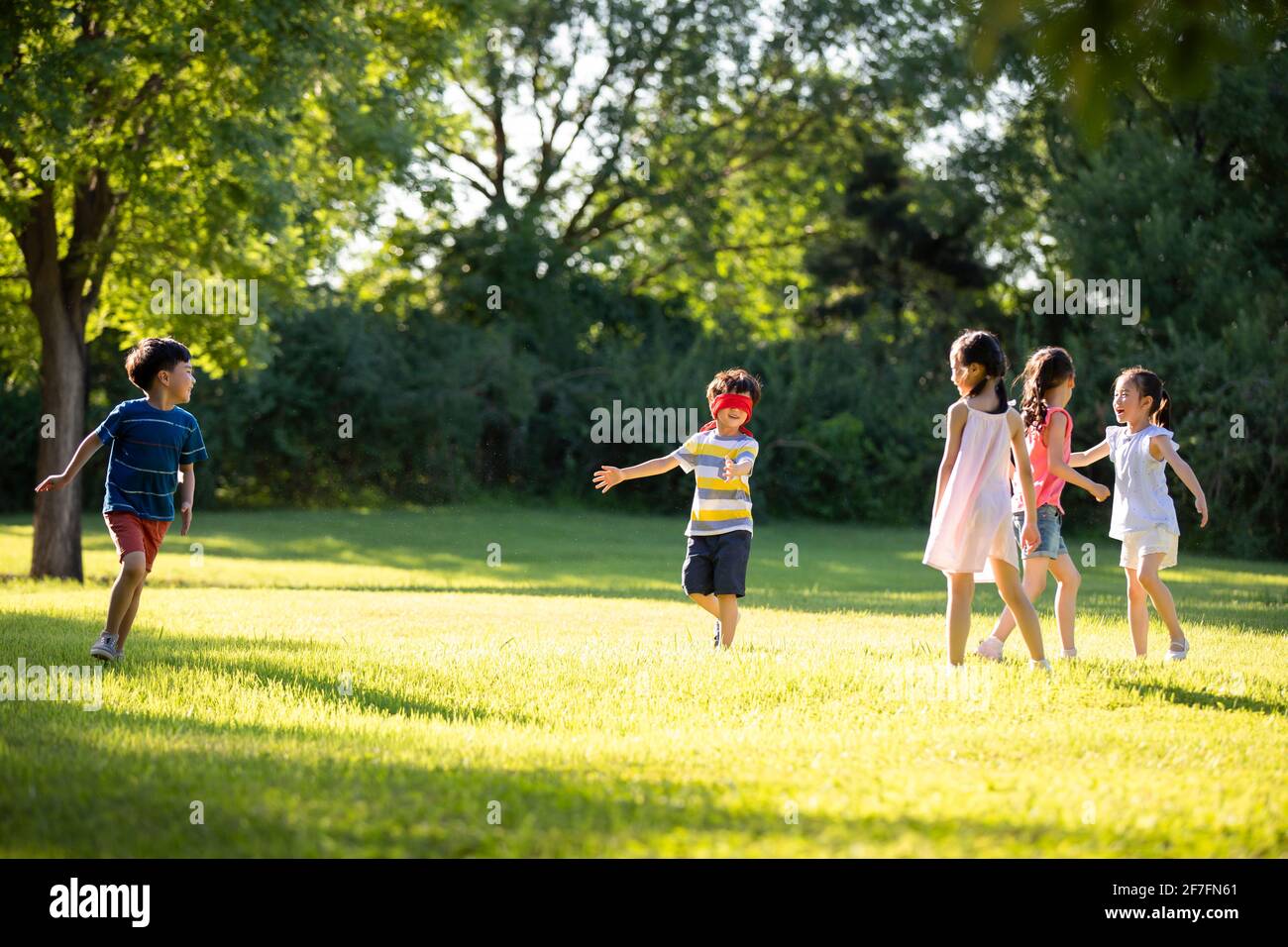 Glückliche Kinder spielen verstecken und suchen auf der Wiese Stockfoto