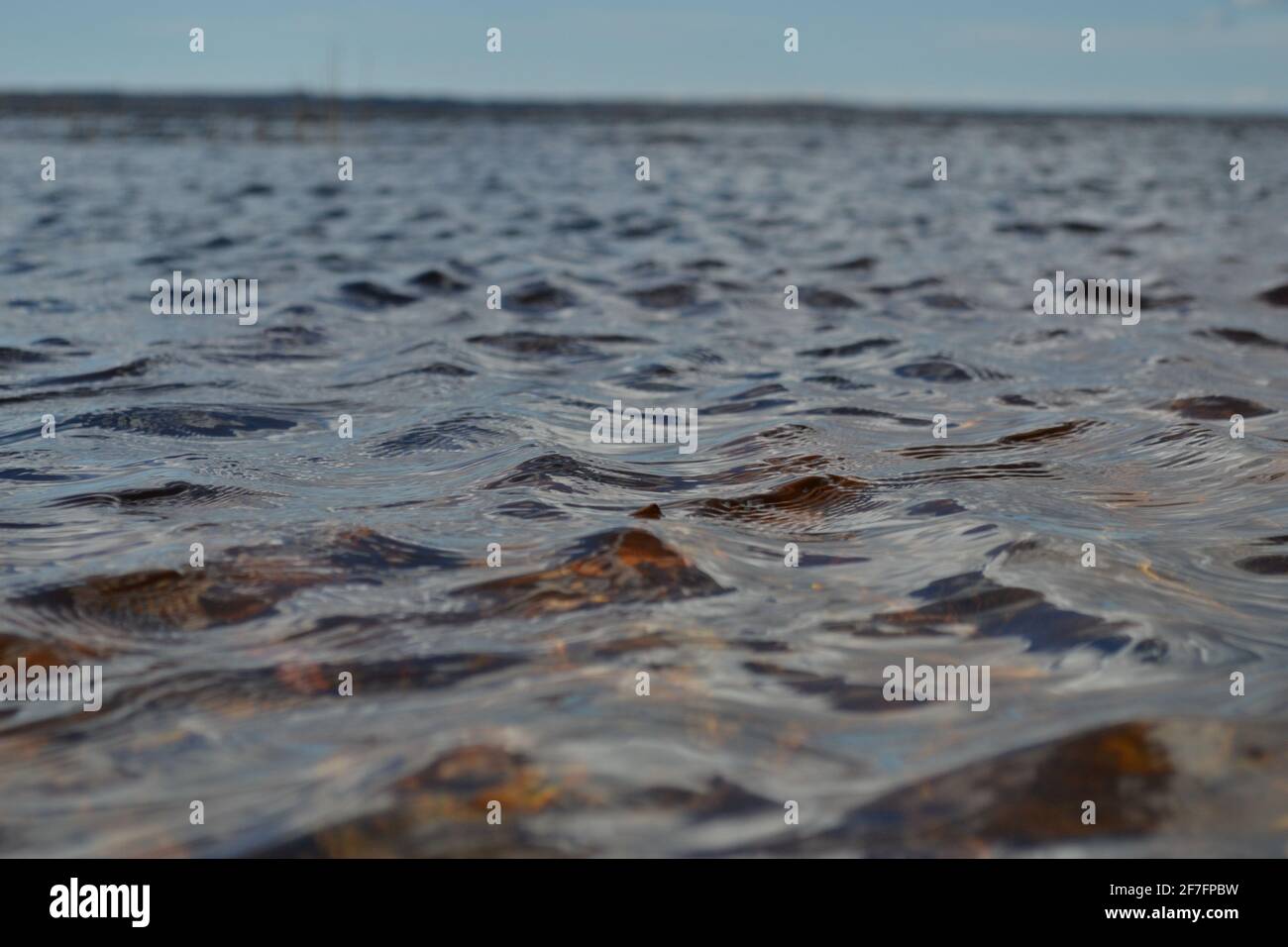 Detaillierte Nahaufnahme von Wasseroberflächen mit Wellen und Wellen und Frühlings-Sonnenlicht, das die Oberfläche reflektiert. Makrofotografie Stockfoto