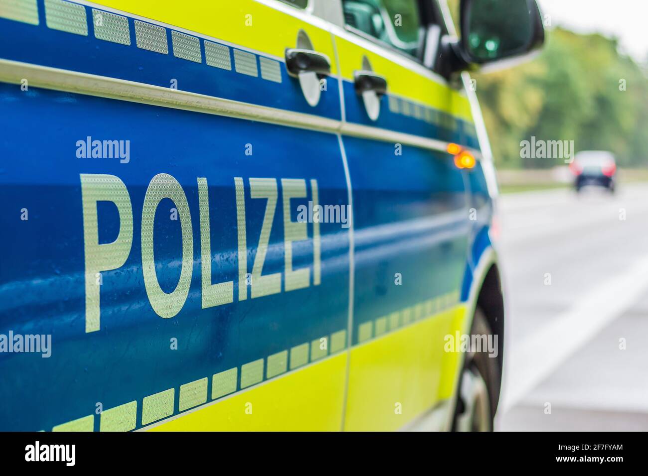 Seitenperspektive der Beifahrerseite des Polizeiwagens auf der Autobahn. Schriftzug Polizei auf dem Körper mit Boom und gelbem Hintergrund. Harte Schulter, Stockfoto