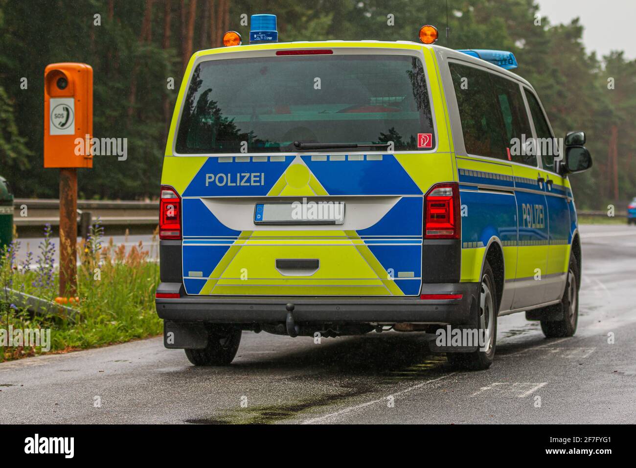 Deutscher Polizeiwagen in einer Nothaltestelle auf einer Autobahn im Land Brandenburg aus der Seitenansicht. Notruftelefon am Straßenrand. Stockfoto