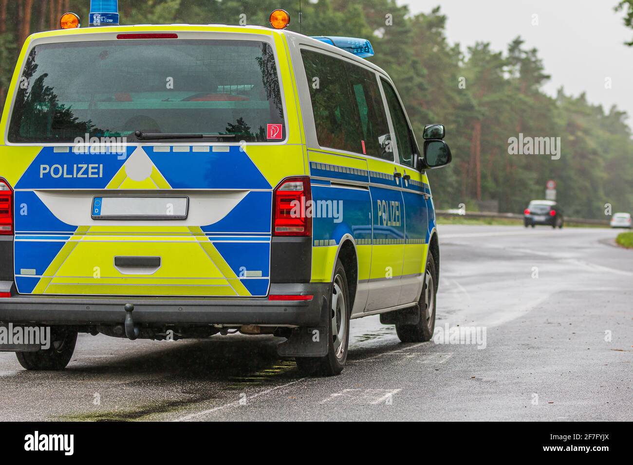 Asphaltierte Straßenoberfläche bei Regenwetter. Polizeiauto auf der Autobahn im Land Brandenburg. Abgewinkelte Ansicht des Fahrzeugs von hinten. Fahrzeuge Stockfoto