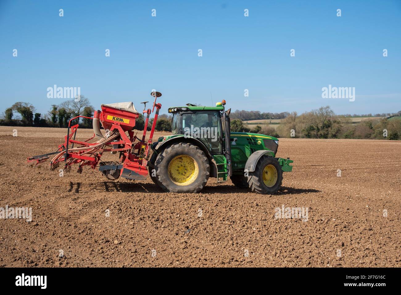Hampshire, England, Großbritannien. 2021. Grüner Traktor mit Sämaschine und nachfolgender Egge bei der Arbeit auf einem Feld in Hampshire Countryside, England, Großbritannien. Stockfoto