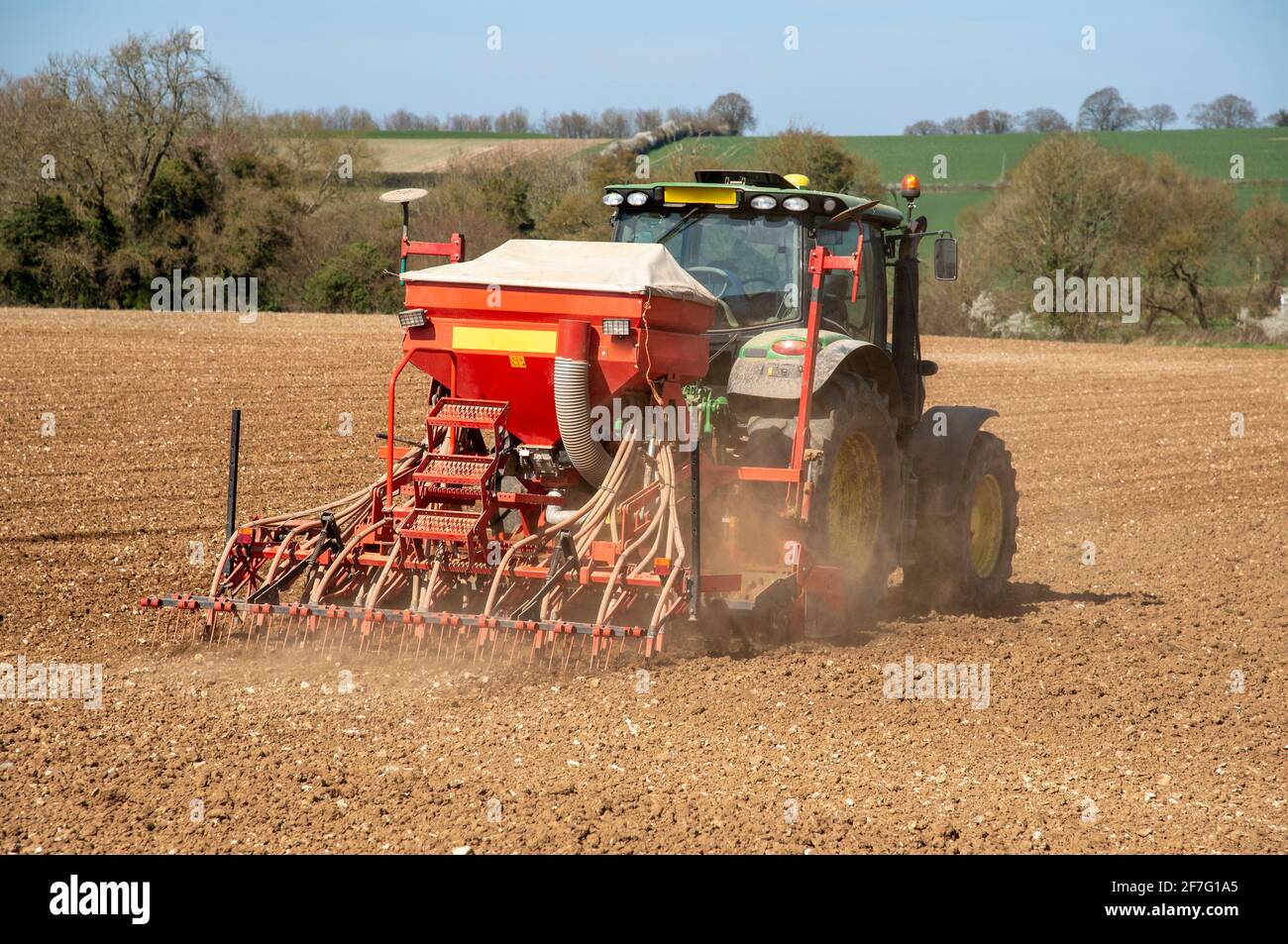 Hampshire, England, Großbritannien. 2021. Grüner Traktor mit Sämaschine und nachfolgender Egge bei der Arbeit auf einem Feld in Hampshire Countryside, England, Großbritannien. Stockfoto