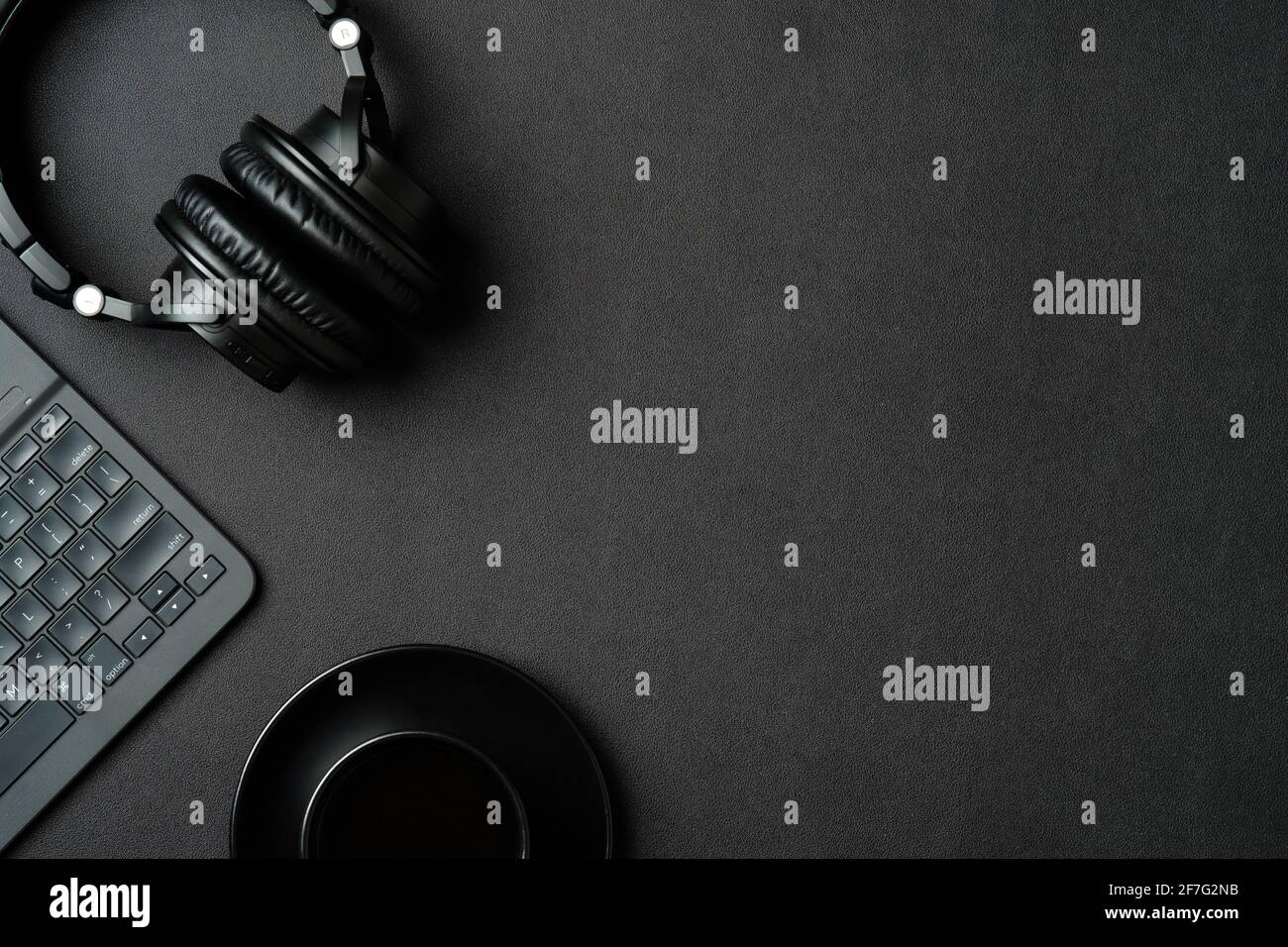 Moderner Schreibtisch mit Kopfhörern, Tasse Kaffee, Laptop-Computer auf schwarzem Lederhintergrund. Flat Lay Sound Producer-Arbeitsplatz. Stockfoto