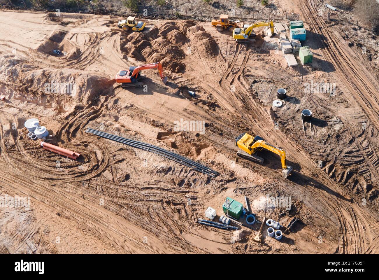 Installation von Sturmwasserkanälen und Bau einer Straße in einem neuen Wohngebiet. Bagger auf Erdarbeiten, Blick von oben, Blick von der Drohne. Ro Stockfoto