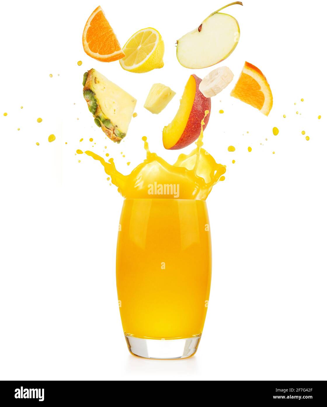 Fruchtstücke, die in ein gelbes Saftglas fallen und spritzen Auf weißem Hintergrund Stockfoto