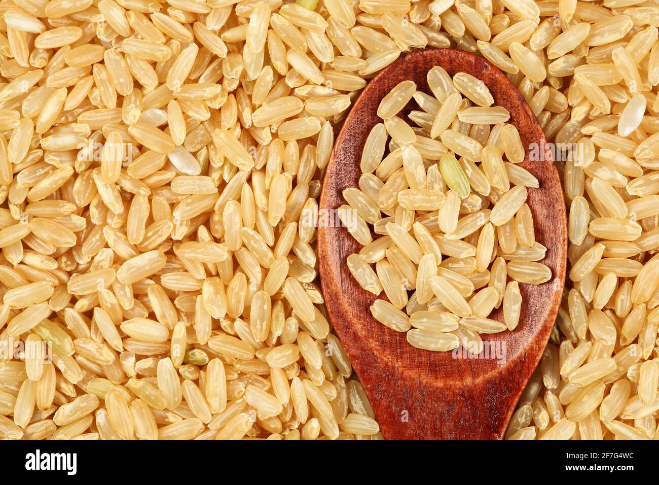 Draufsicht, Nahaufnahme von braunem Vollkornreis mit Holzlöffel Stockfoto