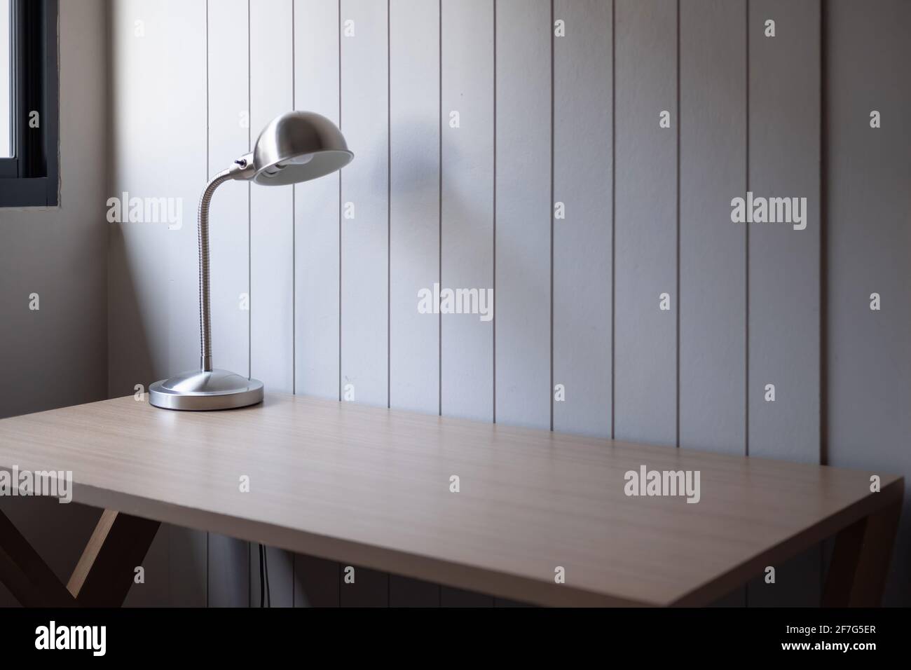 Arbeitsplatz mit Platz - Lampe auf altem Holztisch mit Raum von rauer Zementwand in weißem Farbton Stockfoto