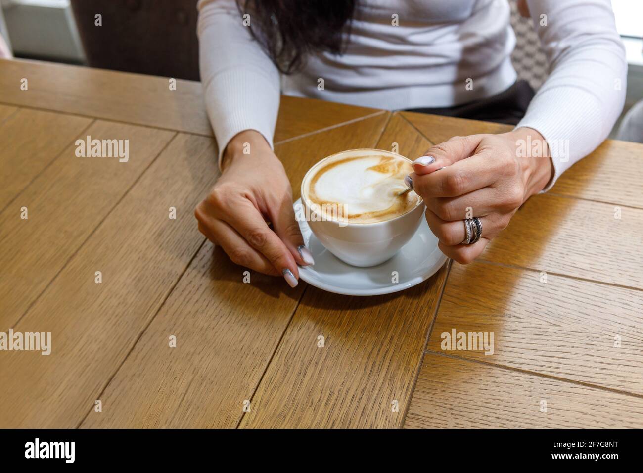 Ein Gast in einem Café rührt Zucker in einer Tasse Kaffee. Das Konzept der Fast Food. Stockfoto