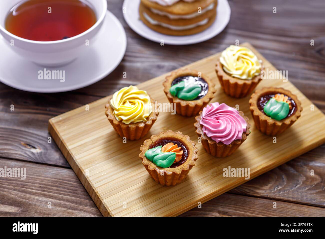 Shortbread und Biskuit und Cremekuchen mit kleinen Blumen und einer Tasse Tee dekoriert. Das Konzept eines festlichen Leckerbissen. Handarbeit Stockfoto