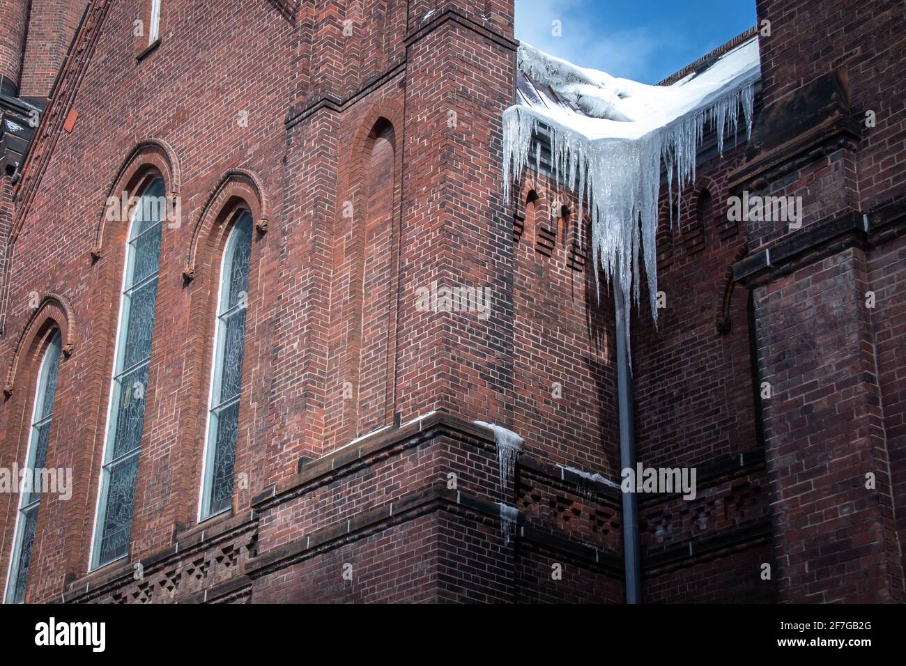 Eiszapfen hängen an einem Wintertag im Februar 2021 an der Seite einer alten Kirche in London, Ontario, Kanada, inmitten von COVID-19 Pandemiesperrungen. Stockfoto