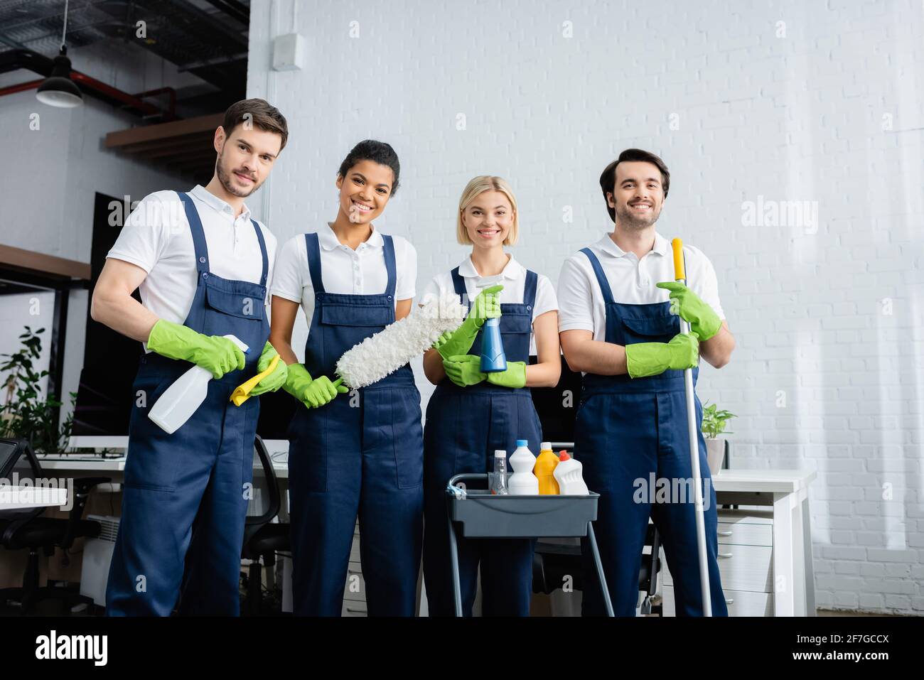Multiethnische Mitarbeiter des Reinigungsdienstes lächeln im Büro vor der Kamera Stockfoto