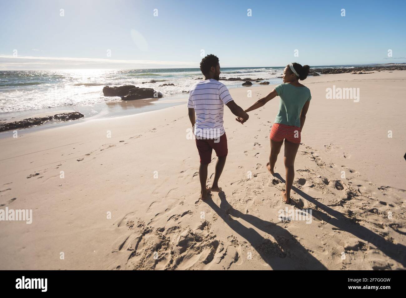 afroamerikanisches Paar, das am Strand mit Händen läuft Stockfoto