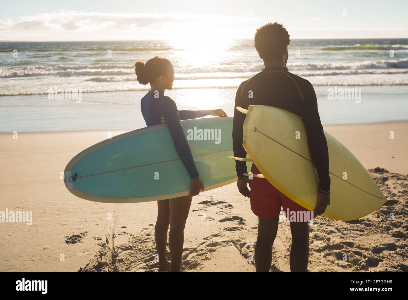 Glückliches afroamerikanisches Paar am Strand mit Surfbrettern Stockfoto