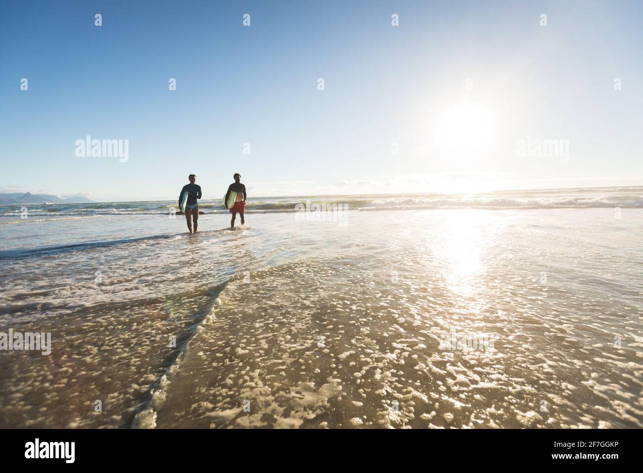 Glückliches afroamerikanisches Paar im Meer mit Surfbrettern Stockfoto