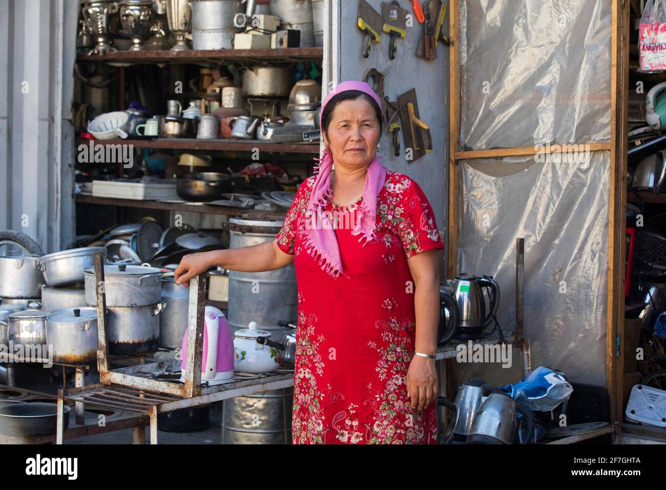 Kirgisische Frau mit Kopftuch verkauft Küchenutensilien, Töpfe und Pfannen auf dem Markt in der Stadt Osch, Kirgisistan Stockfoto