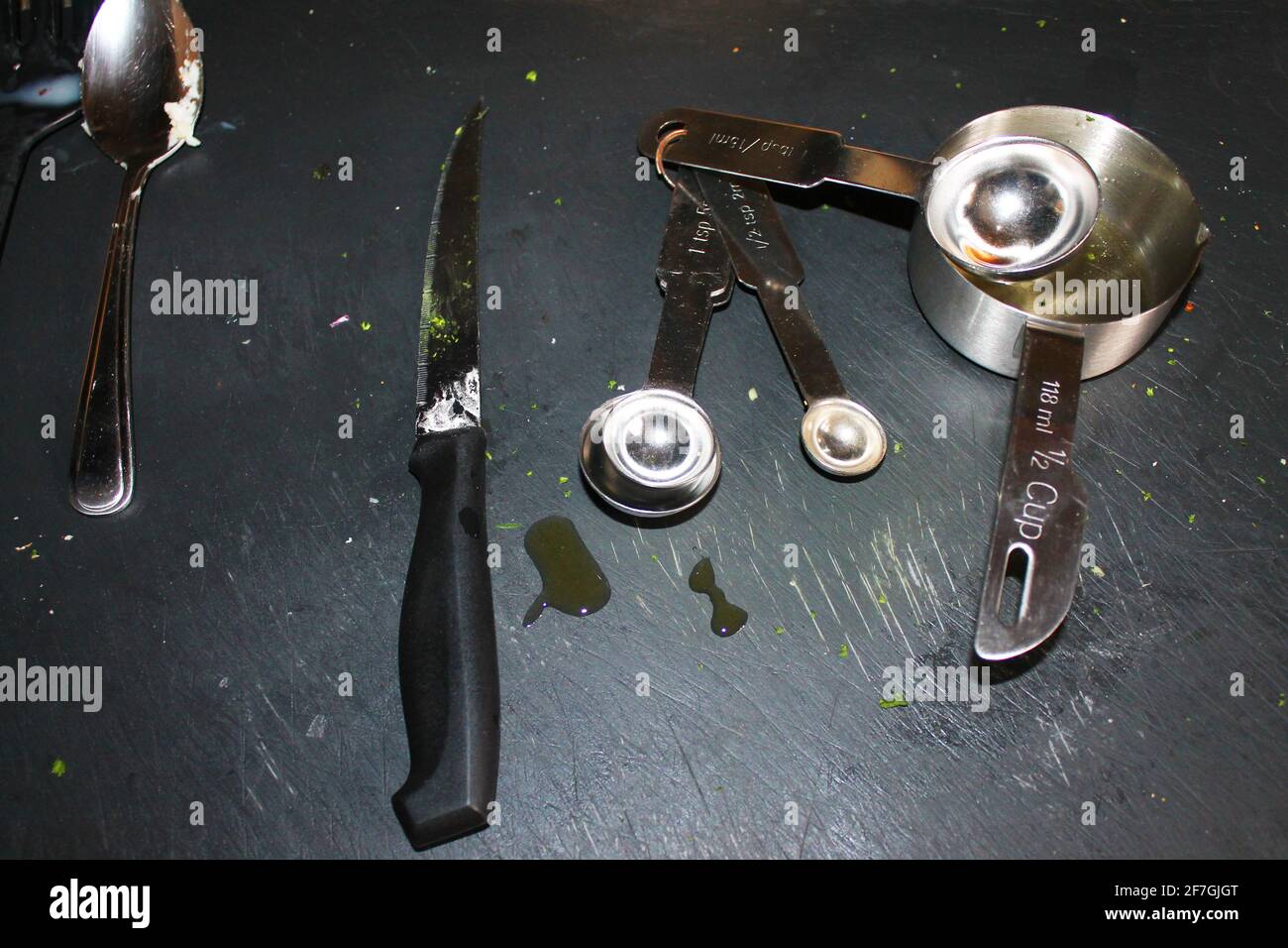 Eine Nahaufnahme von Kochutensilien, die für die Zubereitung von Speisen verwendet wurden, auf einem schwarzen Schiefertafel. Stockfoto