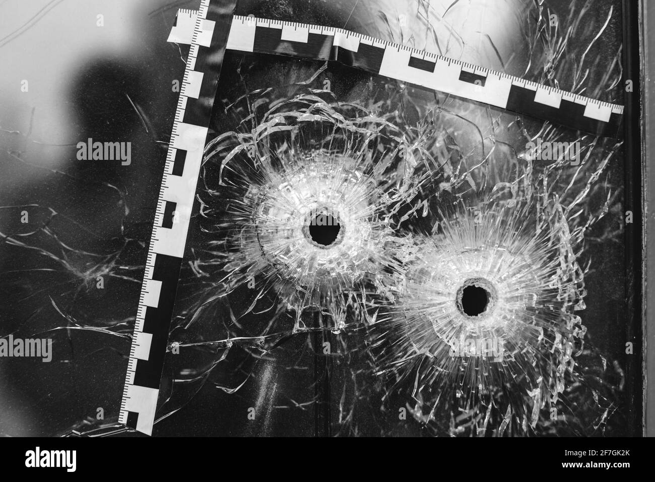 Einschusslöcher in einem Glasfenster, das mit einem gekennzeichnet ist Polizeiband Stockfoto