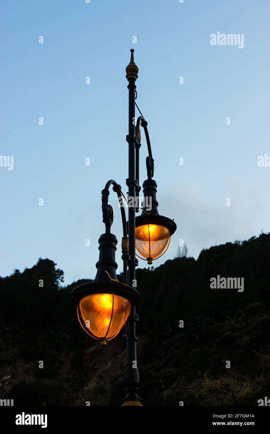 Eine Straßenlampe, orange beleuchtet, mit einem Hintergrund des Himmels Stockfoto