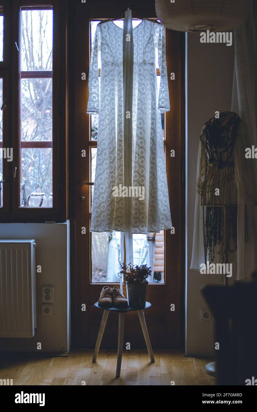 Ein nostalgisches Stillleben-Foto eines Vintage-Brautkleides - gedämpfte Erdtöne, hinterleuchtet durch ein Fenster Stockfoto