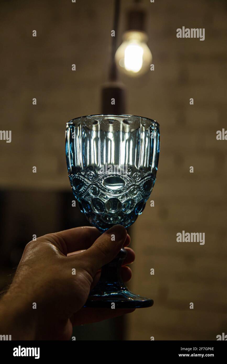 Glas mit Wasser in der Hand draußen und beleuchtete Lampe Hinter Stockfoto