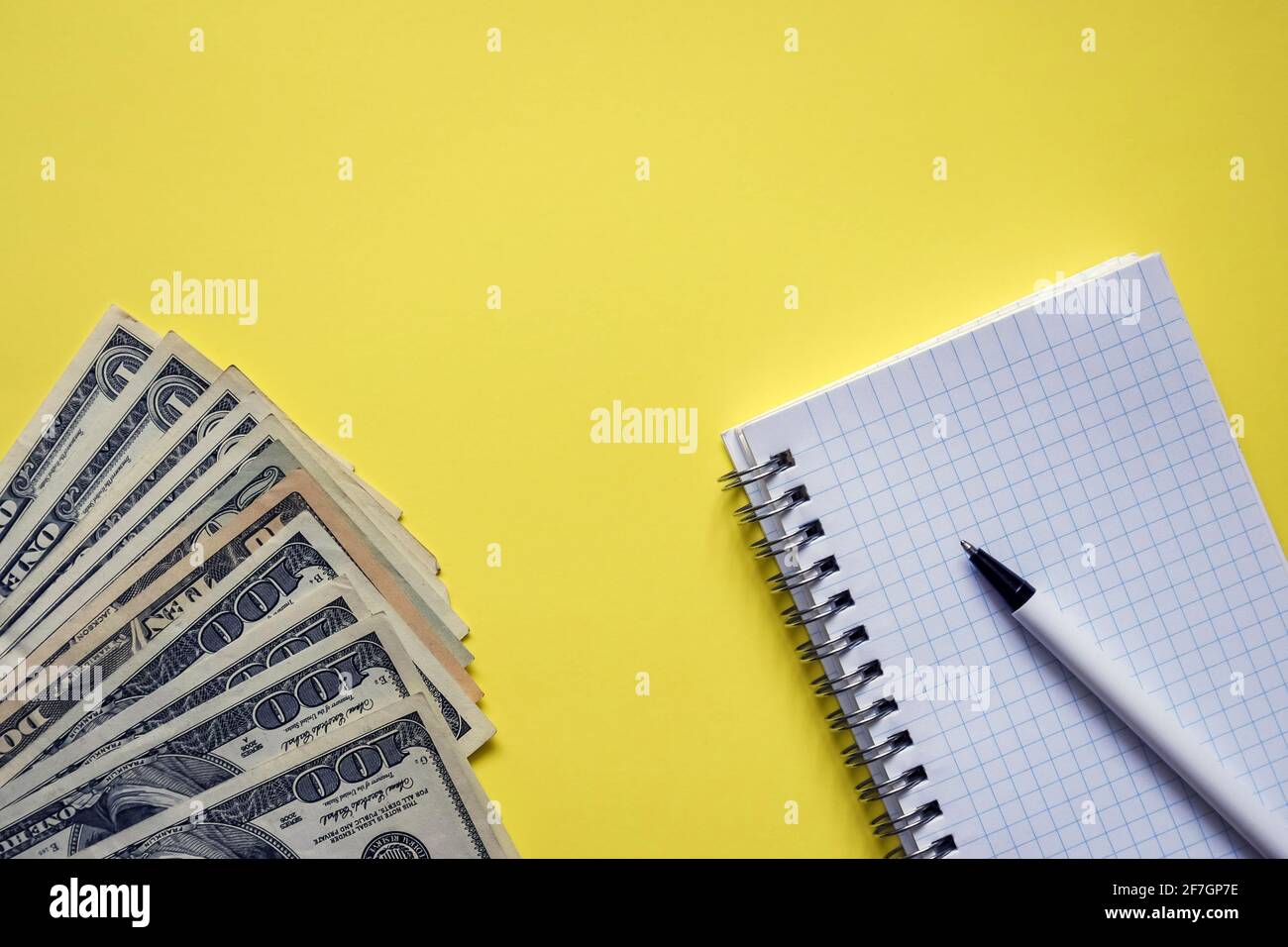 Geschäftselemente - Geldfächer, weißes Notizbuch, Stift auf gelbem Hintergrund. Banknoten verschiedener Stückelungen. Draufsicht. Nahaufnahme. Speicherplatz kopieren Stockfoto