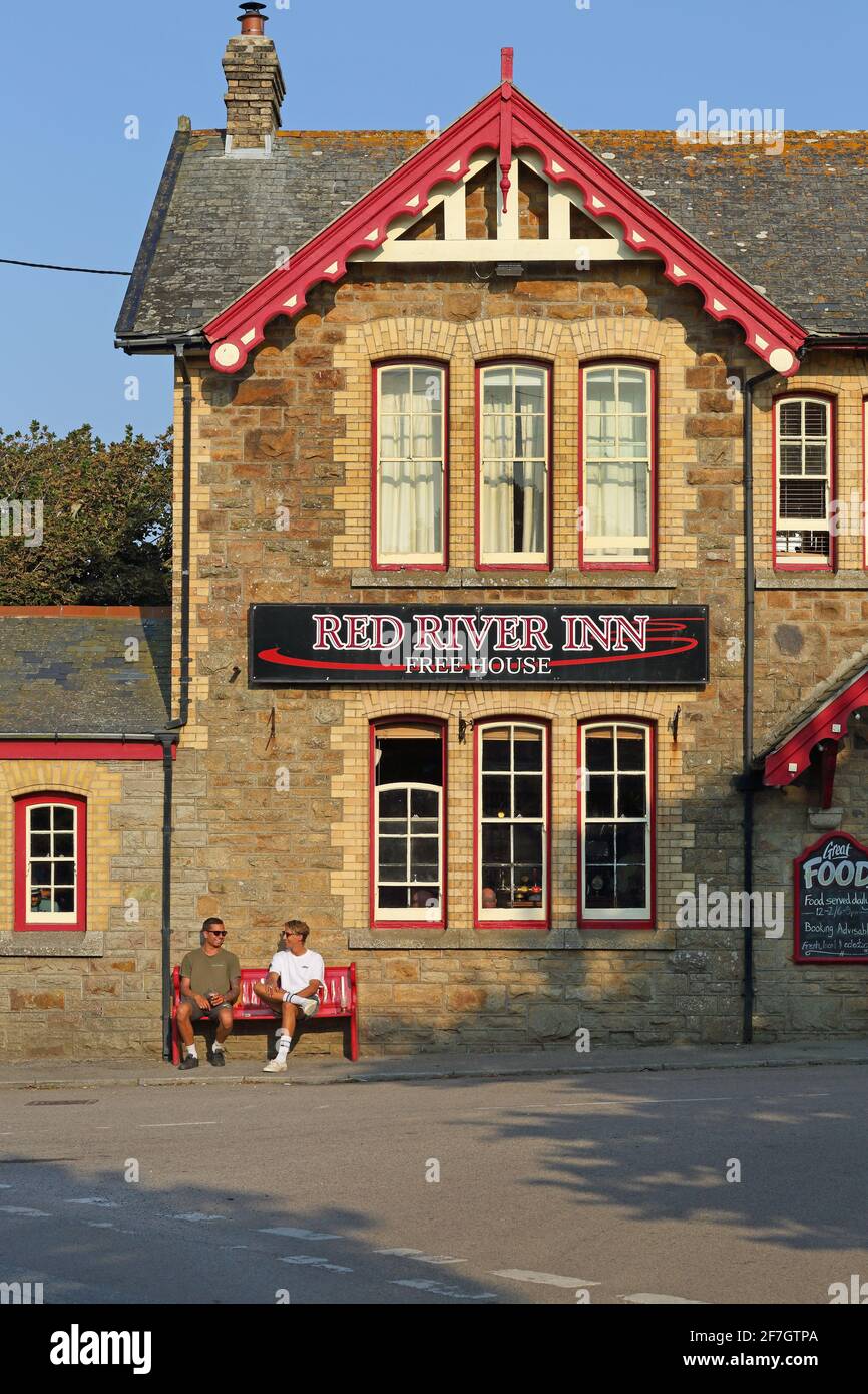 Zwei Leute entspannen sich in der Sonne im Red River Inn im malerischen Küstendorf Gwihian, Cornwall, Großbritannien. Stockfoto
