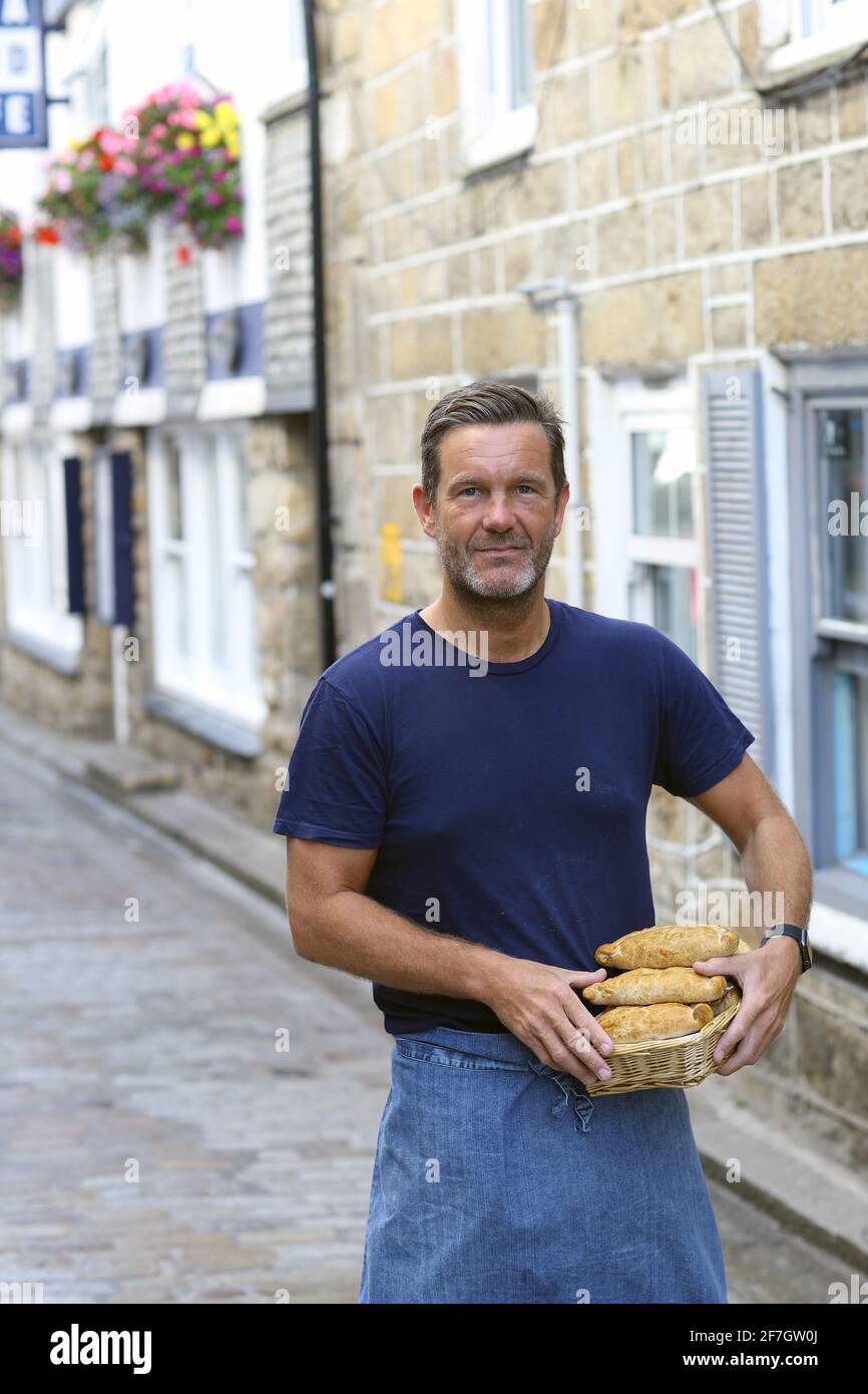 Bäcker vor einem Pasty-Laden, der traditionelle kornische Pastete in St.Ives, Cornwall, Großbritannien, hält Stockfoto