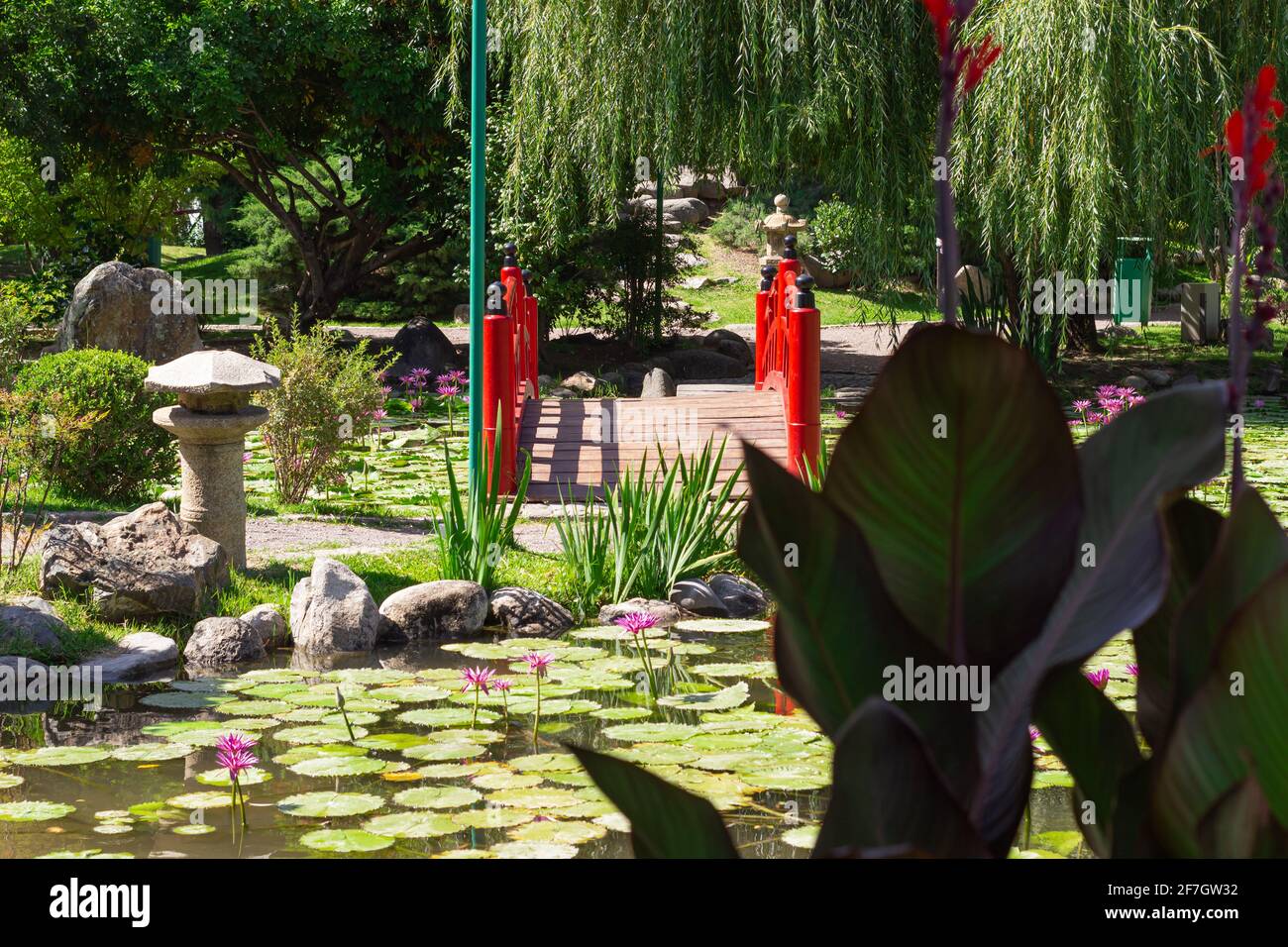 Kleine rote Brücke in einem Stadtpark an einem sonnigen Tag. Stockfoto