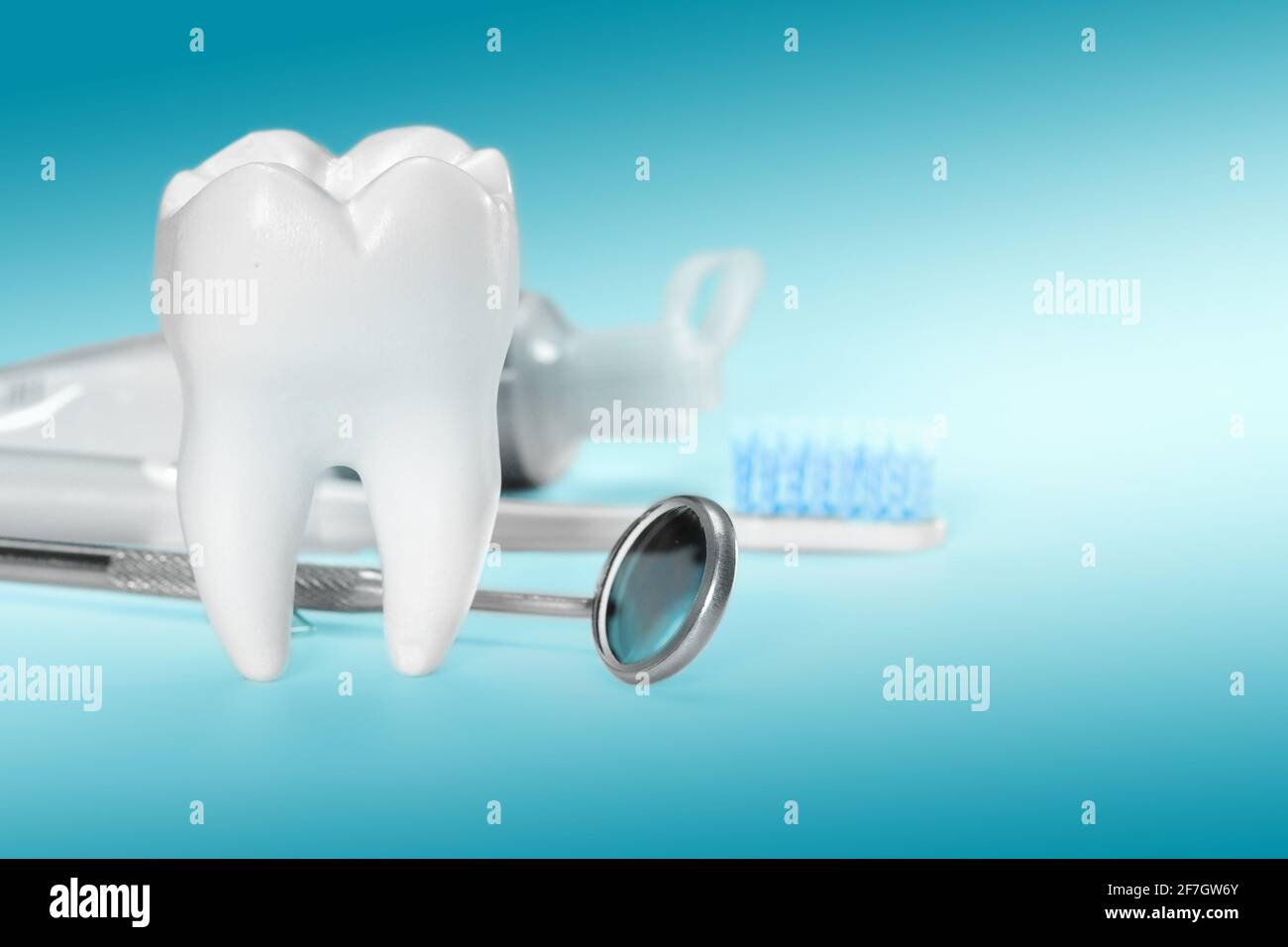 Weißer großer gesunder Zahn und verschiedene Werkzeuge für die Zahnpflege. Auf gradientenem zahnmedizinischem Hintergrund. Stockfoto