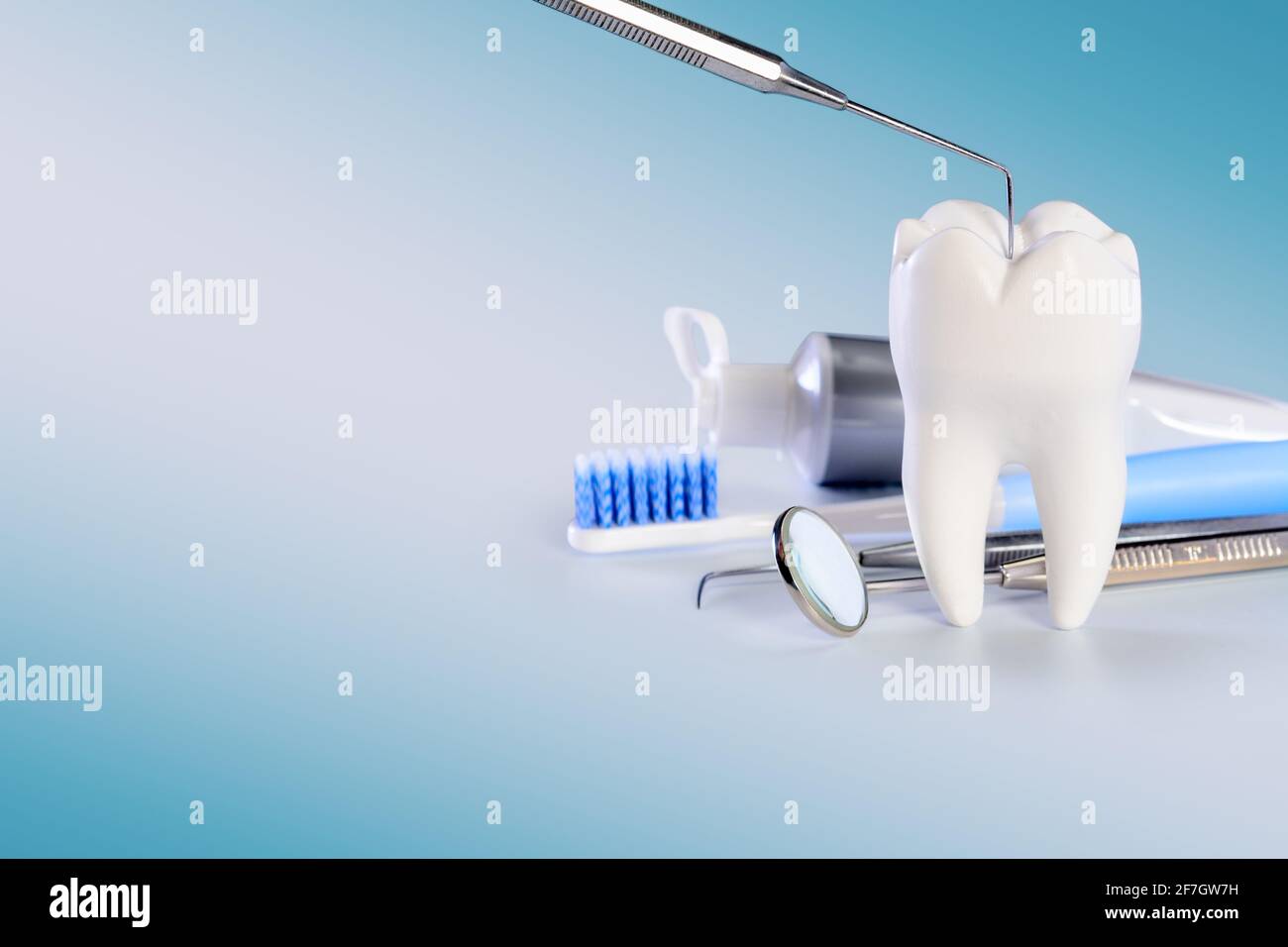 Weißer großer gesunder Zahn und verschiedene Werkzeuge für die Zahnpflege. Auf gradienten zahnmedizinischen Hintergrund mit zahnärztlicher Sonde. Stockfoto