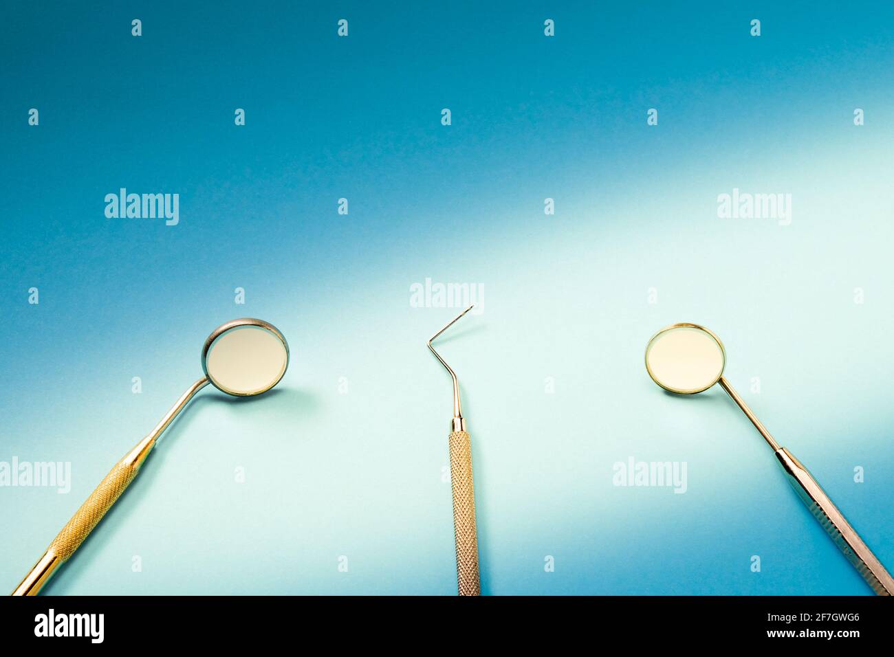 Zahnarztwerkzeuge: Spiegel, Dental Explorer und Pinzette liegen auf blauem  Hintergrund im Lichtstrahl Stockfotografie - Alamy