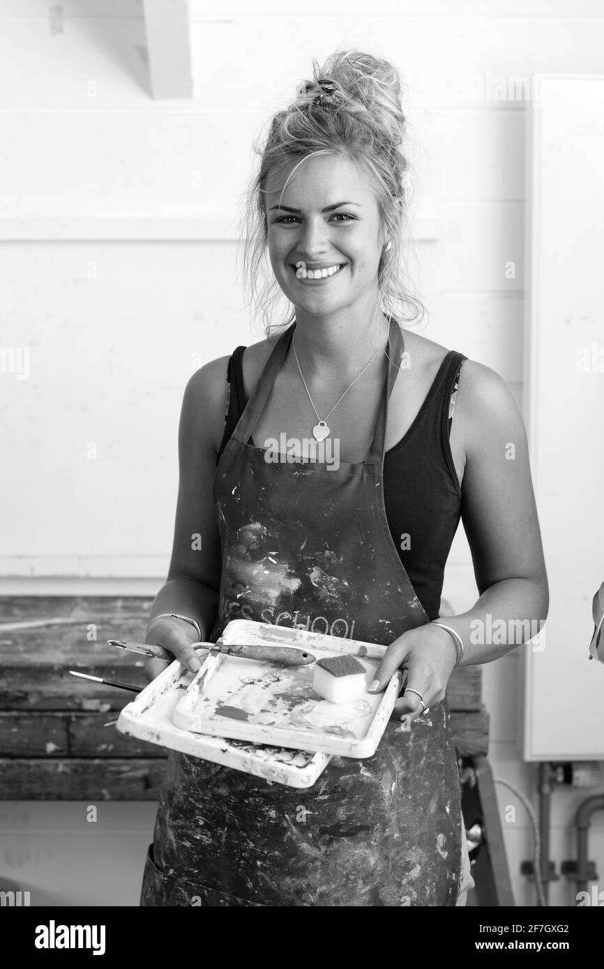 Schöne weibliche bildende Kunst Maler hält eine Palette und Spachtel, und schaffen in seiner Werkstatt. St Ives, Cornwall, England. Stockfoto