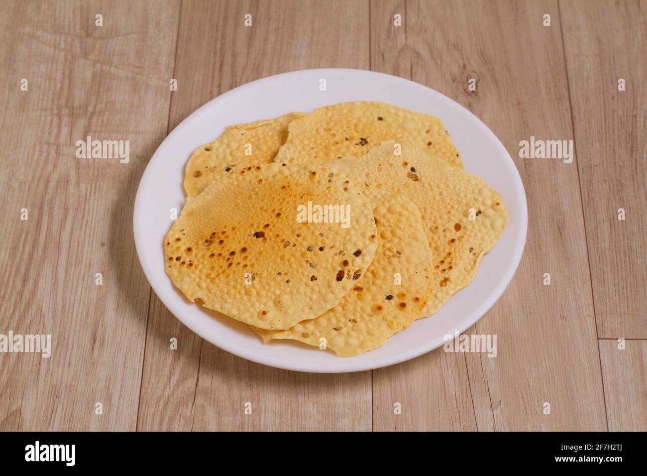 Der runde karierte Fryums Papad ist ein knackiges Snack-Pellets, das auf einer Plate serviert wird. Stockfoto