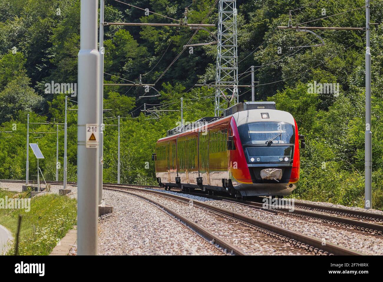 Moderner elektrischer Mehreinheiten-Zug auf offener Schiene. Pendlerzug eilt an einem sonnigen Tag in ländlicher Umgebung in Richtung Stadt. Stockfoto