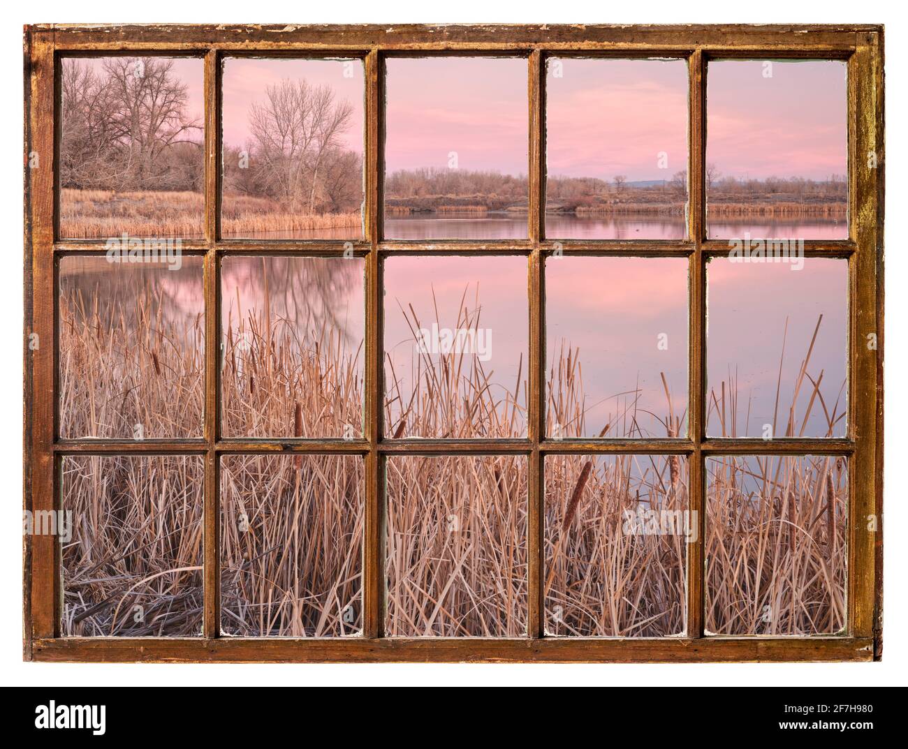 Frühe Frühlingsdämmerung über einem ruhigen See mit Schilf als Von einem alten Kabinenfenster aus gesehen Stockfoto