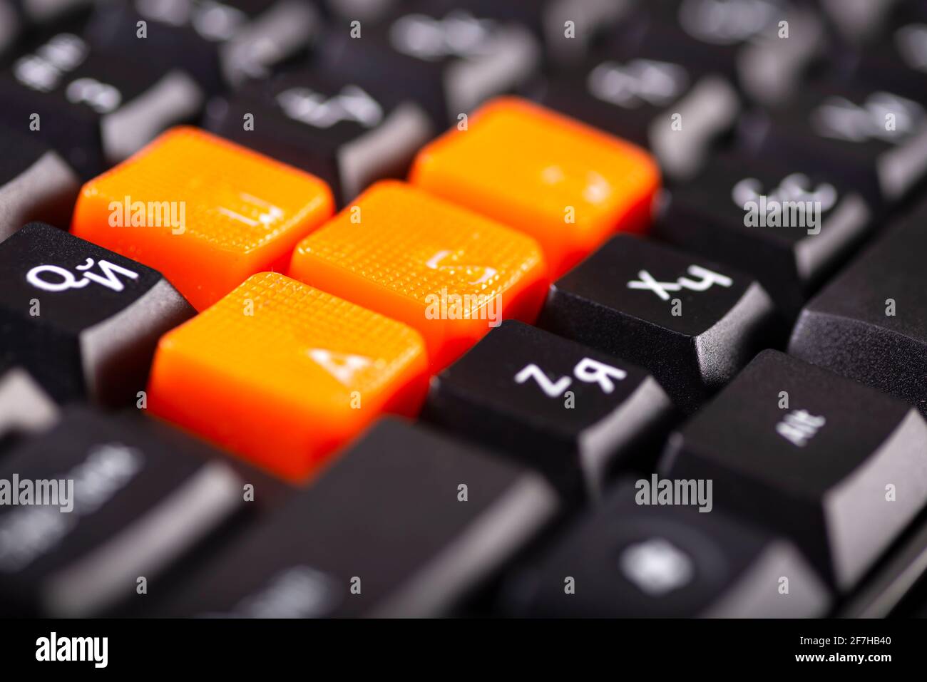 Nahaufnahme der orangefarbenen Pfeiltasten auf einer schwarzen Tastatur,  nach oben, unten, links und rechts auf einer Gaming-Computer-Tastatur  Stockfotografie - Alamy