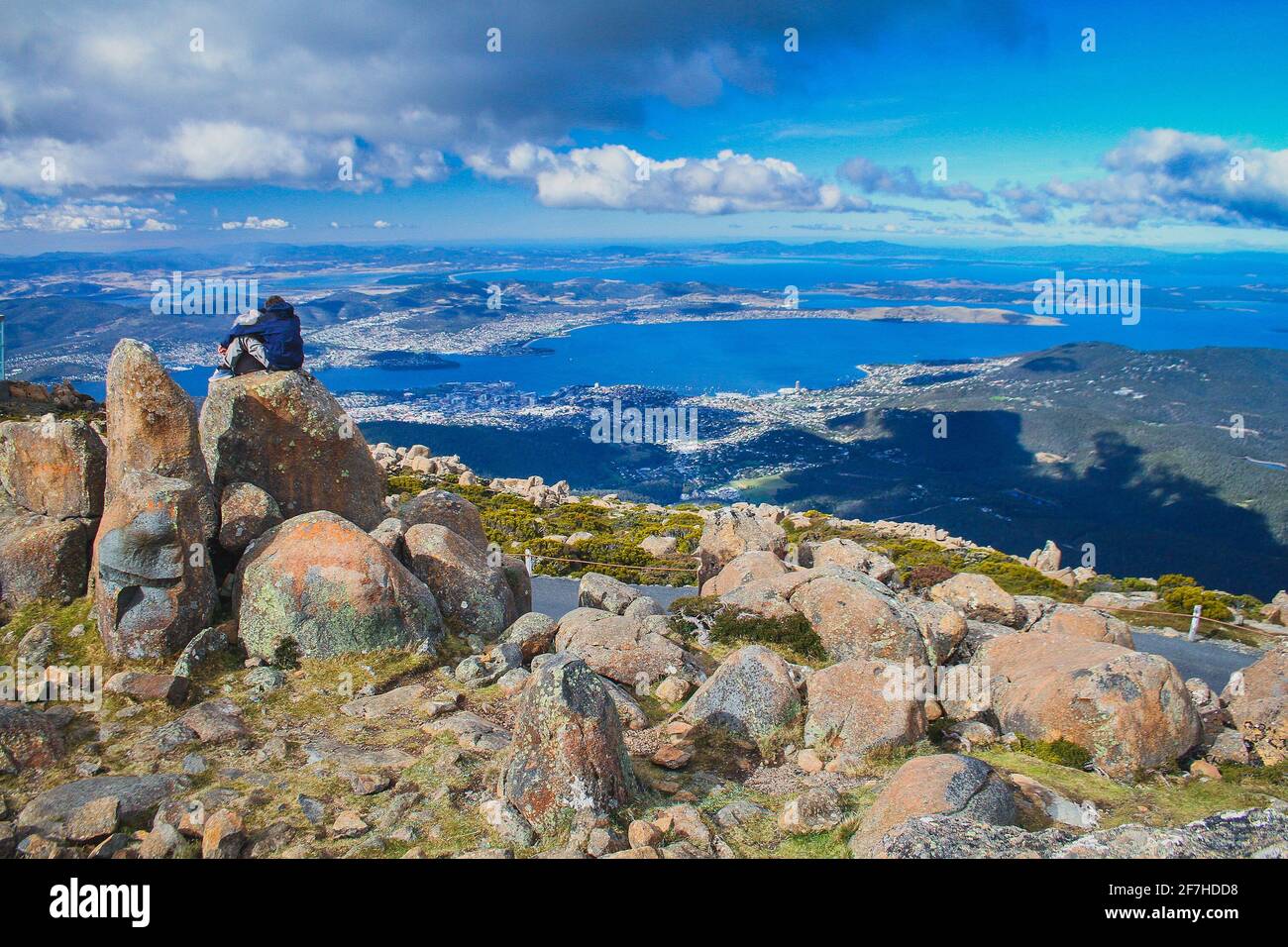 Ein Paar sitzt auf einer Felsformation und genießt den Blick über Hobart vom Gipfel des Mount Wellington, Hobart, Australien. Stockfoto