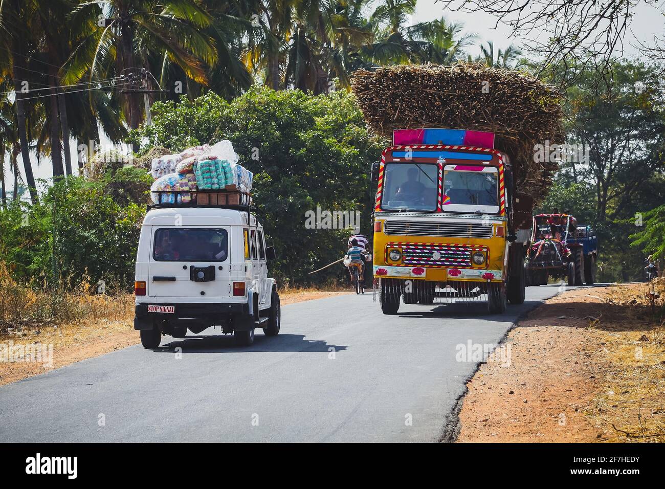 Beladene Lastwagen und andere Fahrzeuge auf einer Landstraße in Indien. Farbenfrohe und überlastete Transportmittel in Indien. Stockfoto